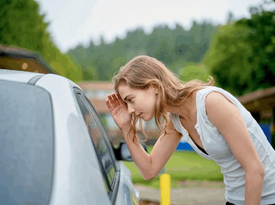 A woman peers through a car window searching for keys during a lockout.