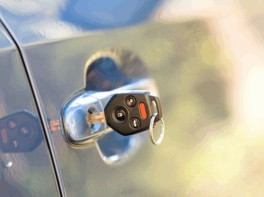 A close-up of a car door with a key stuck in the lock.
