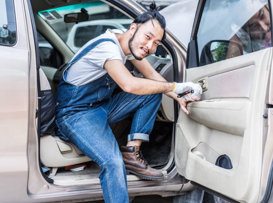 A locksmith smiles after successfully opening a car door to get their client access.