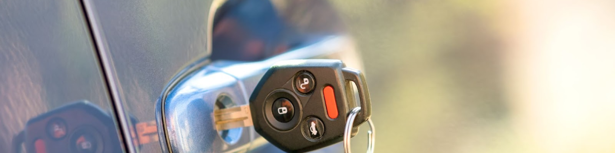 A close-up of a car door with a key stuck in the lock.