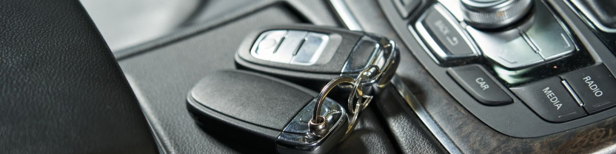 Car keys left on top of a closed glove box beside an audio control unit.