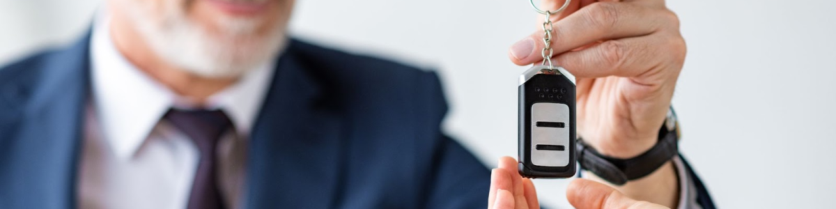 A smiling car dealer gives replacement car keys to female customer.